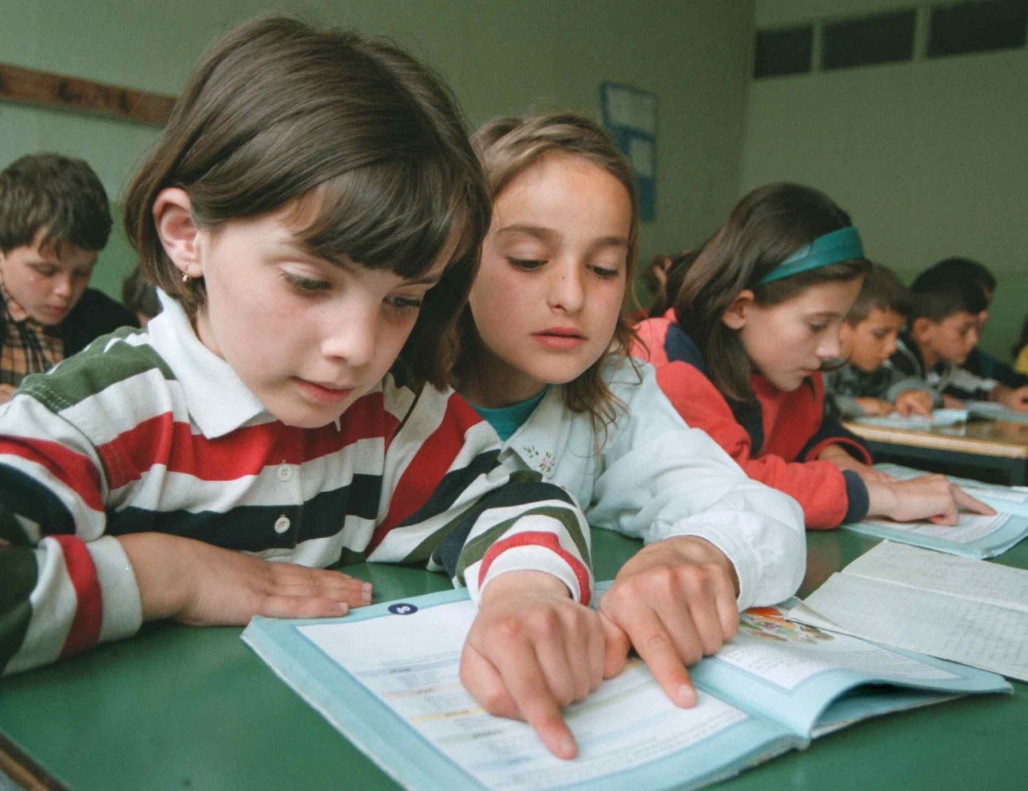 Ethnic Albanian children, refugees from Kosovo, read school books during a lesson in the Macedonian capital Skopje, May 1999. Photo: EPA/GEORGI LICOVSKI/MA-FOB