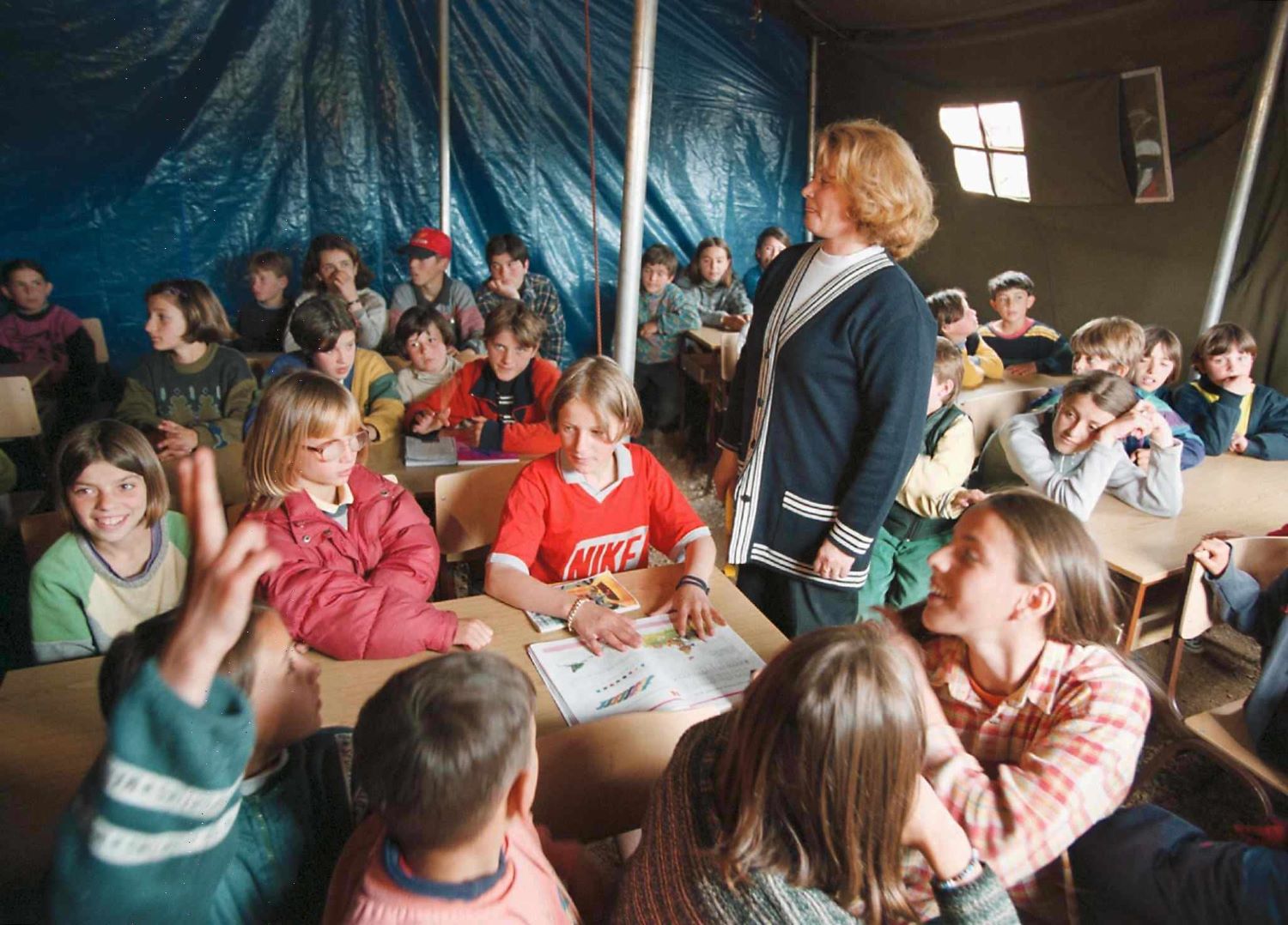 Ethnic Albanian refugees from Kosovo sing songs at an improvised school in a refugee camp near the village of Neprosteno, North Macedonia, May 1999. Photo: EPA/MLADEN ANTONOV/MA-FOB.