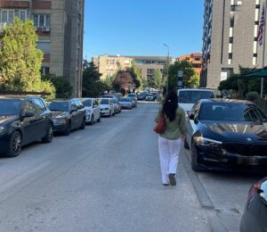 Pedestrian walking on the road due to cars parked on the pavement in the 'Aktash' neighbourhood in Prishtina. Photo: BIRN