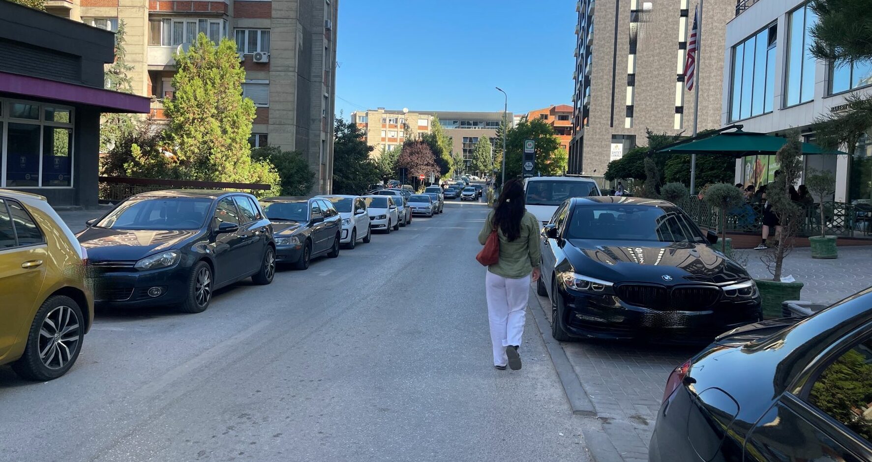 Pedestrian walking on the road due to cars parked on the pavement in the 'Aktash' neighbourhood in Prishtina. Photo: BIRN