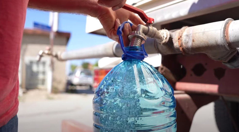 Ciziten filling cans with clean water from a water tank in Hajvalia. Photo: BIRN