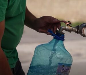 A citizen fills plastic jerrycans with clean water from a water tank truck in Hajvalia. Photo: BIRN