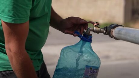 A citizen fills plastic jerrycans with clean water from a water tank truck in Hajvalia. Photo: BIRN