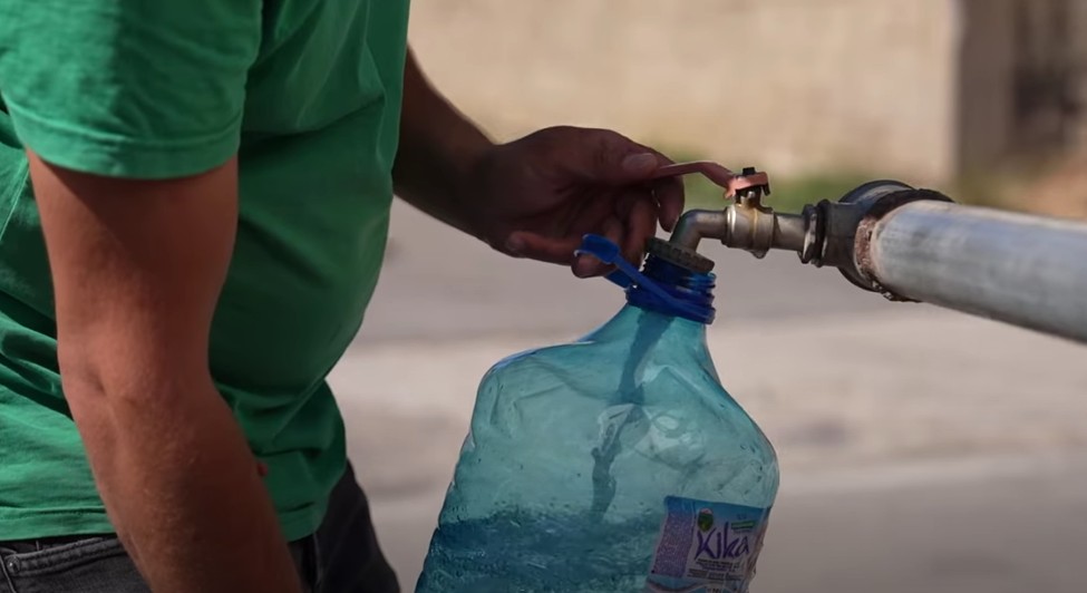 A citizen fills plastic jerrycans with clean water from a water tank truck in Hajvalia. Photo: BIRN
