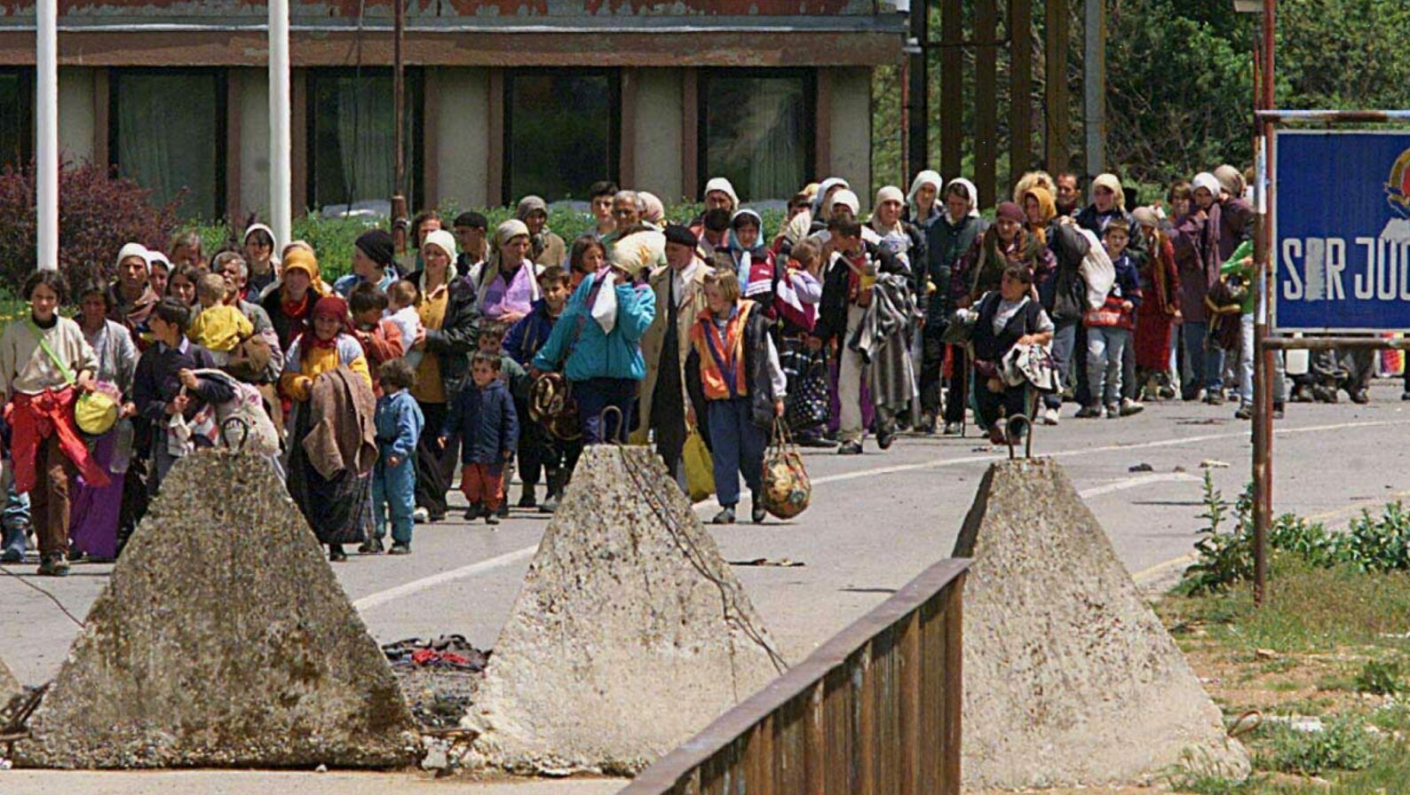 Ethnic Albanian refugees fleeing Kosovo are passing by anti-tank obstacles as they arrive after hours on foot at the Yugoslav-Albanian border in Morina on Monday, May 10, 1999. Photo: EPA/Louisa Gouliamaki/lg-fob